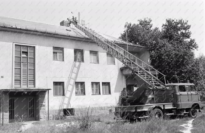Peremarton, 1985. augusztus 16. Tűzoltólétráról bontják az életveszélyessé vált kéményt Peremartonban, a földrengést követően. Megkezdődött a károk helyreállítása és felmérése. MTI Fotó: Hámor Szabolcs