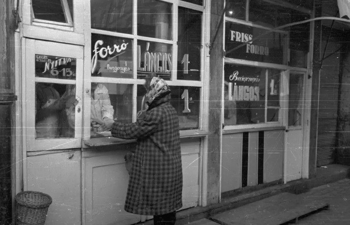 1965-ben feltehetően Budapesten egy hölgyet szolgálnak ki burgonyás lángossal. Forrás: Fortepan/Bauer Sándor